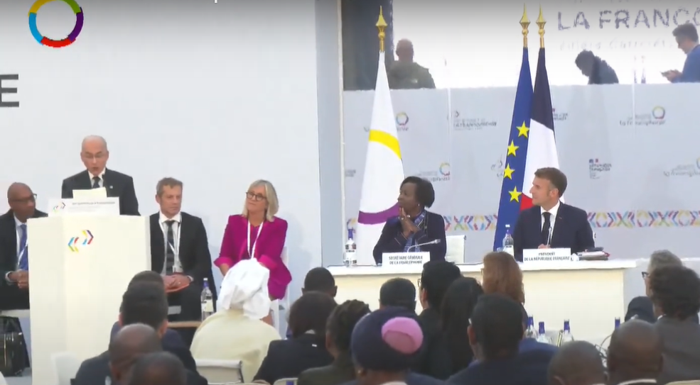 អ្នកស្រី ល្វីស មូស៊ីគីវ៉ាបូ ដែលកំពុងអង្គុយនៅតុគណៈអធិបតីជាមួយលោក ម៉ាក្រុង លើកដៃប្រណម ពេលព្រះមហាក្សត្រកម្ពុជា យាងថ្លែងព្រះរាជសុន្ទរកថា។&nbsp;